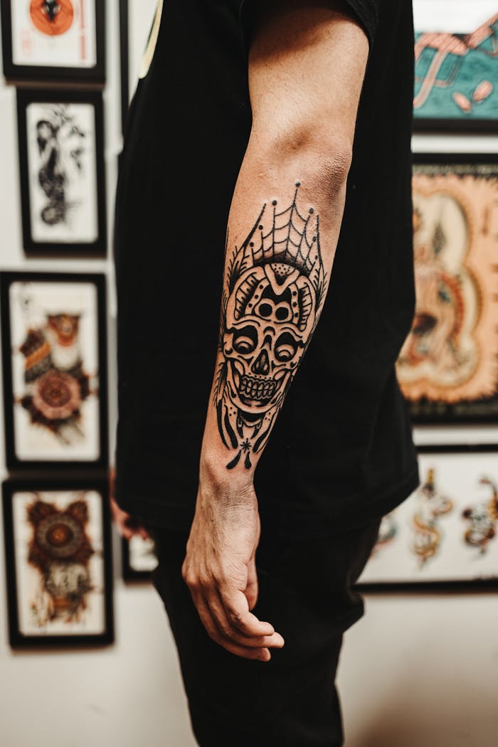 Detailed close-up of a man's arm with an intricate skull tattoo in an artistic setting.